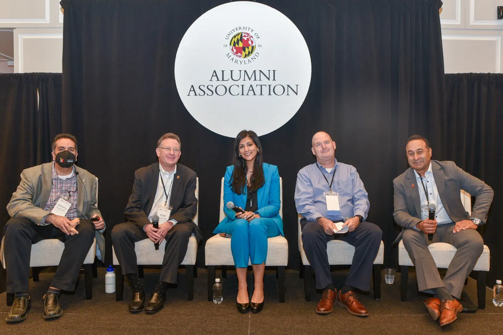 Five speakers, including Evan Shubin, sit on stage in front of the Alumni Association logo.
