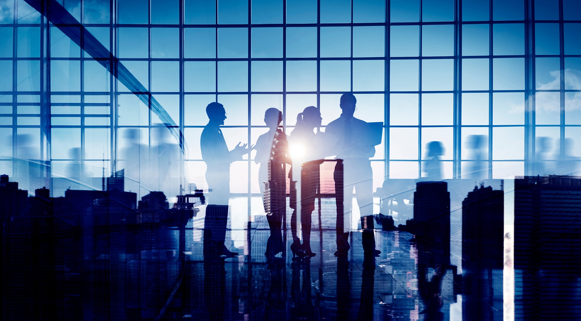 Silhouetted business professionals meeting in a glass office with city skyline backdrop.