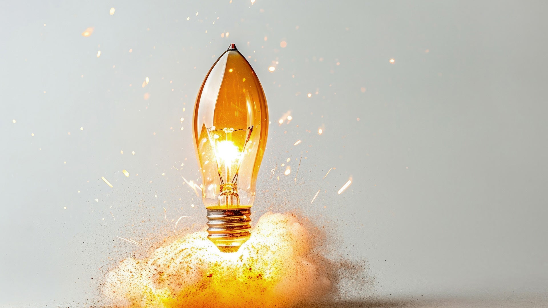 A glowing light bulb launches like a rocket amid orange sparks and smoke against a gray background.