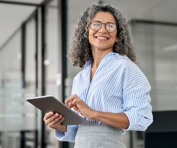 Professional woman smiling while holding a tablet in a modern office setting
